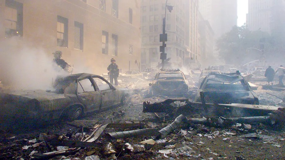 Cars smoulder in the street as the destroyed World Trade Center burns in New York on Sept. 11, 2001.
